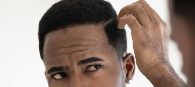 Shirtless man with hairy chest checks for dandruff in the mirror