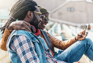 Black man with dreads hanging with friend looking at phone