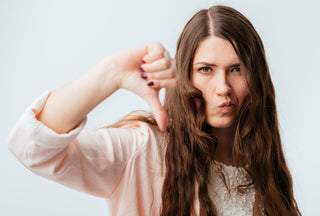  Chica morena de cabello largo con el cabello graso que muestra el pulgar hacia abajo aislado sobre un fondo blanco