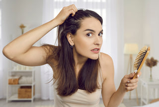 Retrato de una mujer en los años 30 mirando su reflejo con expresión nerviosa horrorizada mientras nota la caspa del cuero cabelludo y la acumulación de productos