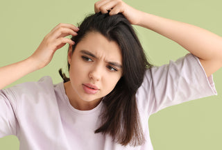 Mujer joven con picazón en el cuero cabelludo y problema de caspa escamosa examinando su cabello sobre fondo verde