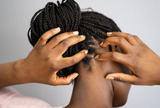 African-American woman with braids scratching the back of her itchy scalp.